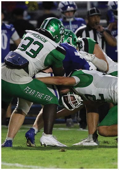 A person wearing a green football uniform with the number 4 is running on a football field while holding a football. Descripci n generada con IA