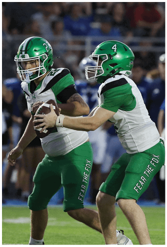 A person wearing a green sports jersey with the number 34 is in the foreground while a crowd of people watches in the background. Descripci n generada con IA