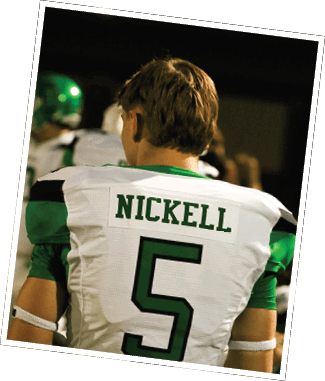 A person wearing a white and green football jersey with the name “Nickell" and the number 5 on the back is standing with other similarly dressed people in the background. Descripci n generada con IA