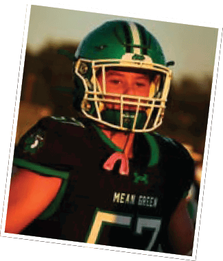 A person wearing a green and black football uniform with the number 57 and a helmet is standing outdoors during sunset. Descripci n generada con IA