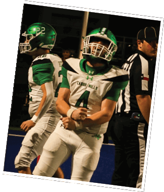 Two people in green and white football uniforms with helmets are on a field, one flexing their arms while the other stands nearby. Descripci n generada con IA
