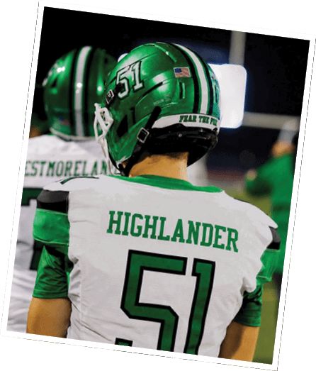 A person in green football gear and helmet is crouched in a ready stance on a grassy field. Descripci n generada con IA