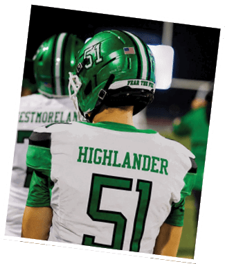 Two people wearing football helmets and uniforms are engaged in a play on a football field at night, with one person grabbing the other's jersey. Descripci n generada con IA
