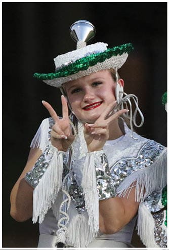 A person wearing a sequined and fringed costume with a decorative hat is making a peace sign and puckering their lips. Descripci n generada con IA