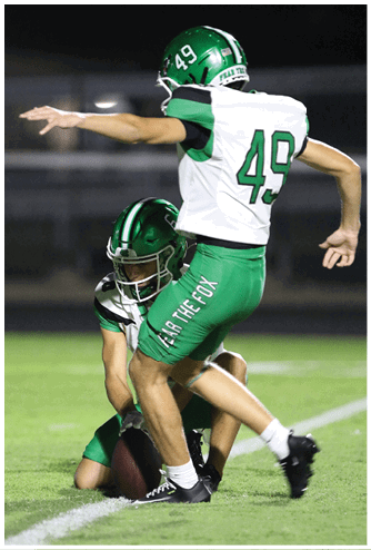 A person wearing a green sports jersey with the number 34 is in the foreground while a crowd of people watches in the background. Descripci n generada con IA