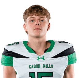 A person stands facing forward wearing a white and green sports uniform with the number 15 and the words “CYPRESS MILLS" on the jersey. Descripci n generada con IA