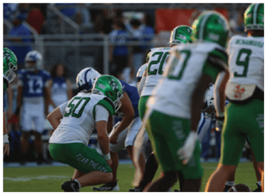 A group of people wearing green and white football uniforms are lined up on a grassy field, preparing for a play during a game. Descripci n generada con IA