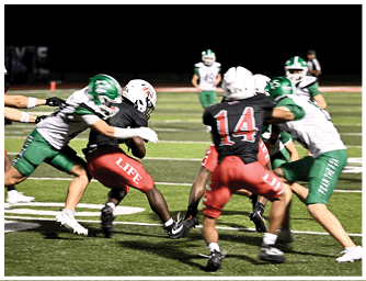 Players in green and black football uniforms are actively engaged in a tackle during a nighttime game on a field with yard lines. Descripci n generada con IA
