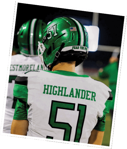A person in green football gear and helmet is crouched in a ready stance on a grassy field. Descripci n generada con IA