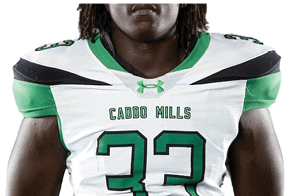 A person wearing a white and green football jersey with the number 33 and the words Caddo Mills on the front. Descripci n generada con IA