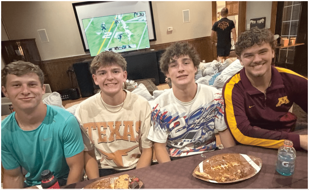 A group of people sitting and standing around tables in a room with a “Seniors Class of 2023" banner, eating and socializing. Description generated by AI