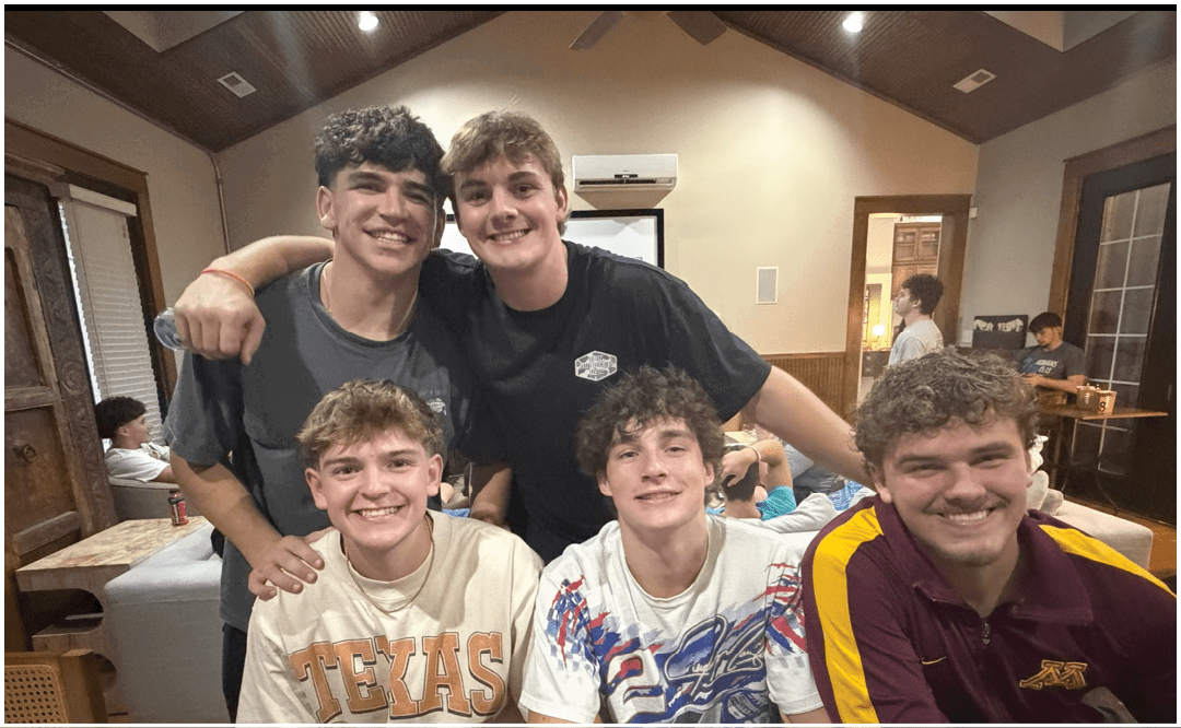 A group of people sitting and standing around tables in a room with a “Seniors Class of 2023" banner, eating and socializing. Description generated by AI