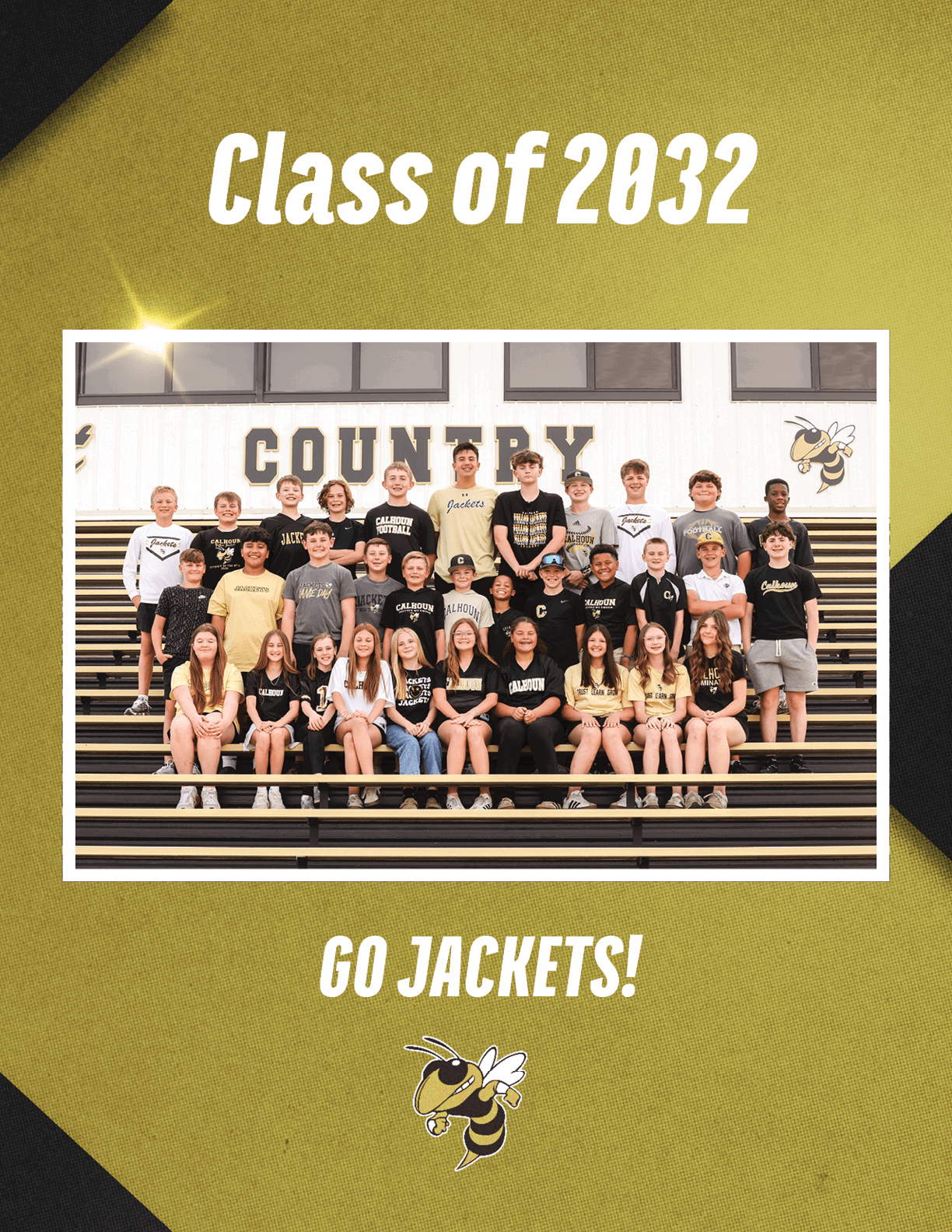 A group of children wearing school spirit shirts pose on bleachers in front of a wall with the word “COUNTRY" and a yellow jacket mascot with text above reading "Class of 2032" and below reading "GO JACKETS!" Description generated by AI