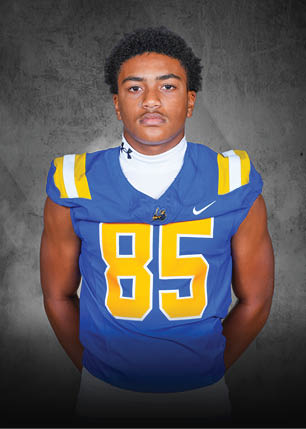 A young man wearing a white and black jersey with the number 14 on it. Description generated by AI