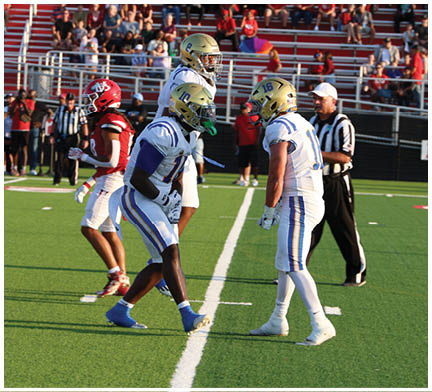 A group of football players huddled together on the field. Description generated by AI