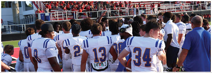 A group of football players on a field. Description generated by AI