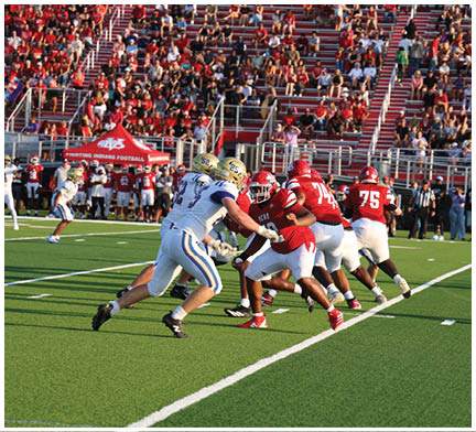 A group of football players huddled together on the field. Description generated by AI