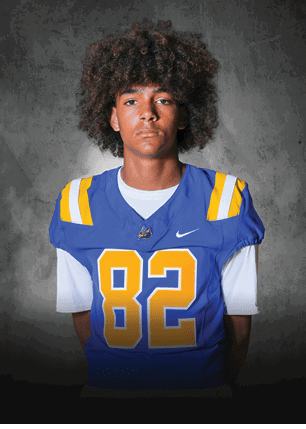 A young man wearing a white and black jersey with the number 14 on it. Description generated by AI