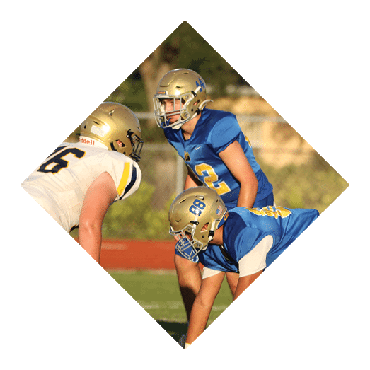 A football player wearing a black jersey with the number 10 sits on the ground with a football helmet on the ground next to him. AI generated content