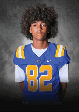 A young man wearing a white and black jersey with the number 14 on it. Description generated by AI