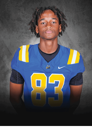 A young man wearing a white and black jersey with the number 14 on it. Description generated by AI