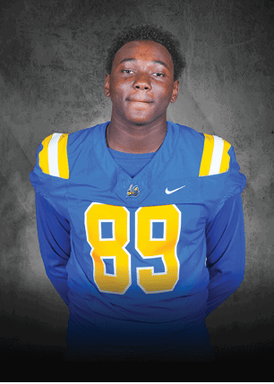 A young man wearing a white and black jersey with the number 14 on it. Description generated by AI