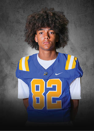 A young man wearing a white and black jersey with the number 14 on it. Description generated by AI