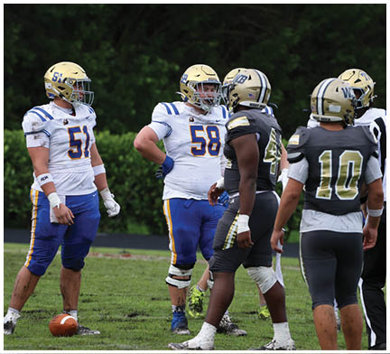 A group of football players huddled together on the field. Description generated by AI