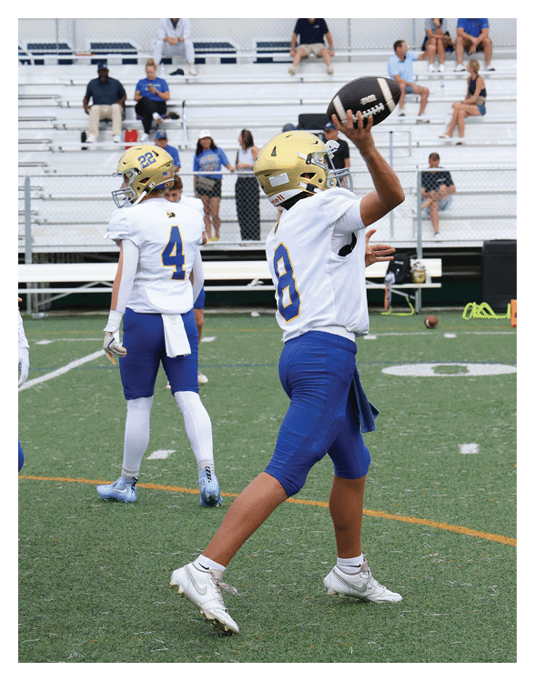 A football player wearing a helmet and white uniform is holding his helmet above his head. AI generated content