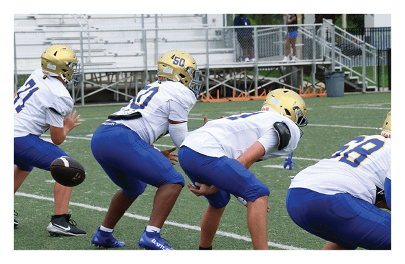 A group of people are kneeling on a field, possibly in a football game. AI generated content
