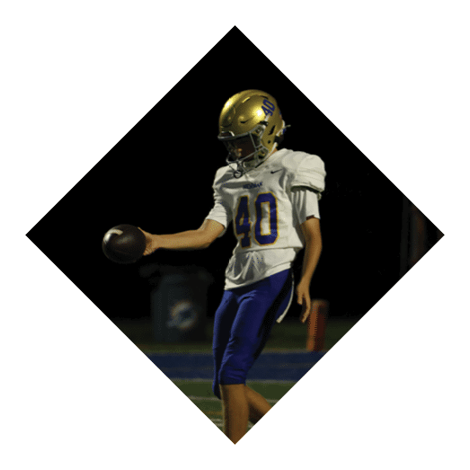 A football player wearing a black jersey with the number 10 sits on the ground with a football helmet on the ground next to him. AI generated content