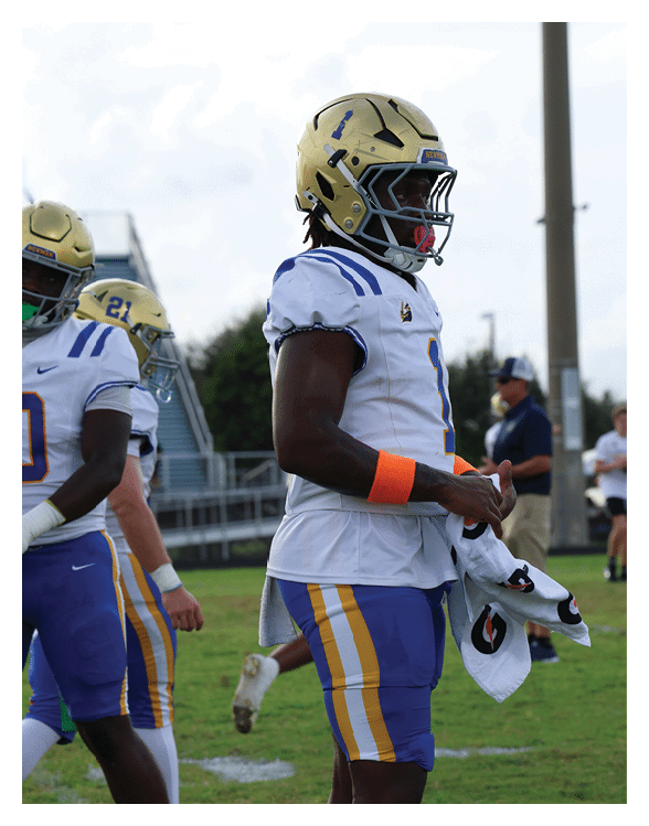 A football player wearing a helmet and white uniform is holding his helmet above his head. AI generated content