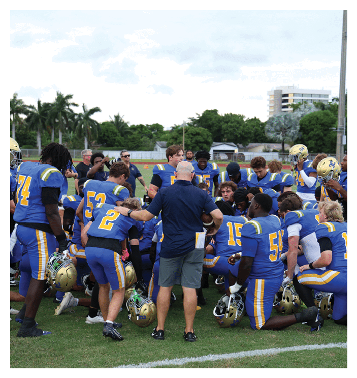 A football game is in progress with players on the field. One player is throwing a football while another player is trying to catch it. The players are wearing uniforms and are actively engaged in the game. AI generated content