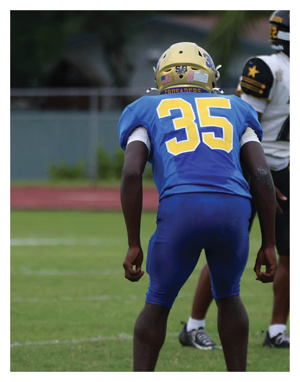 A football player wearing a helmet and white uniform is holding his helmet above his head. AI generated content