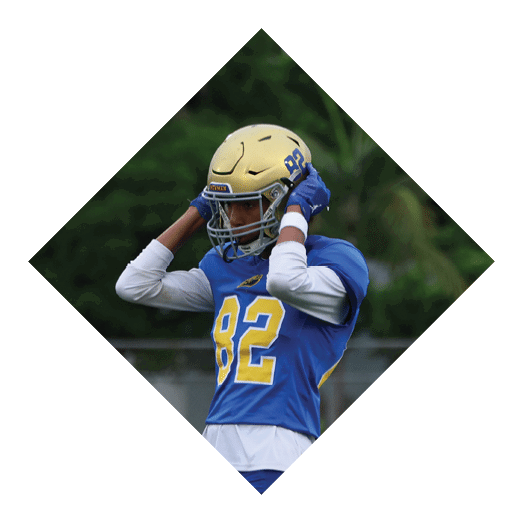 A football player wearing a black jersey with the number 10 sits on the ground with a football helmet on the ground next to him. AI generated content