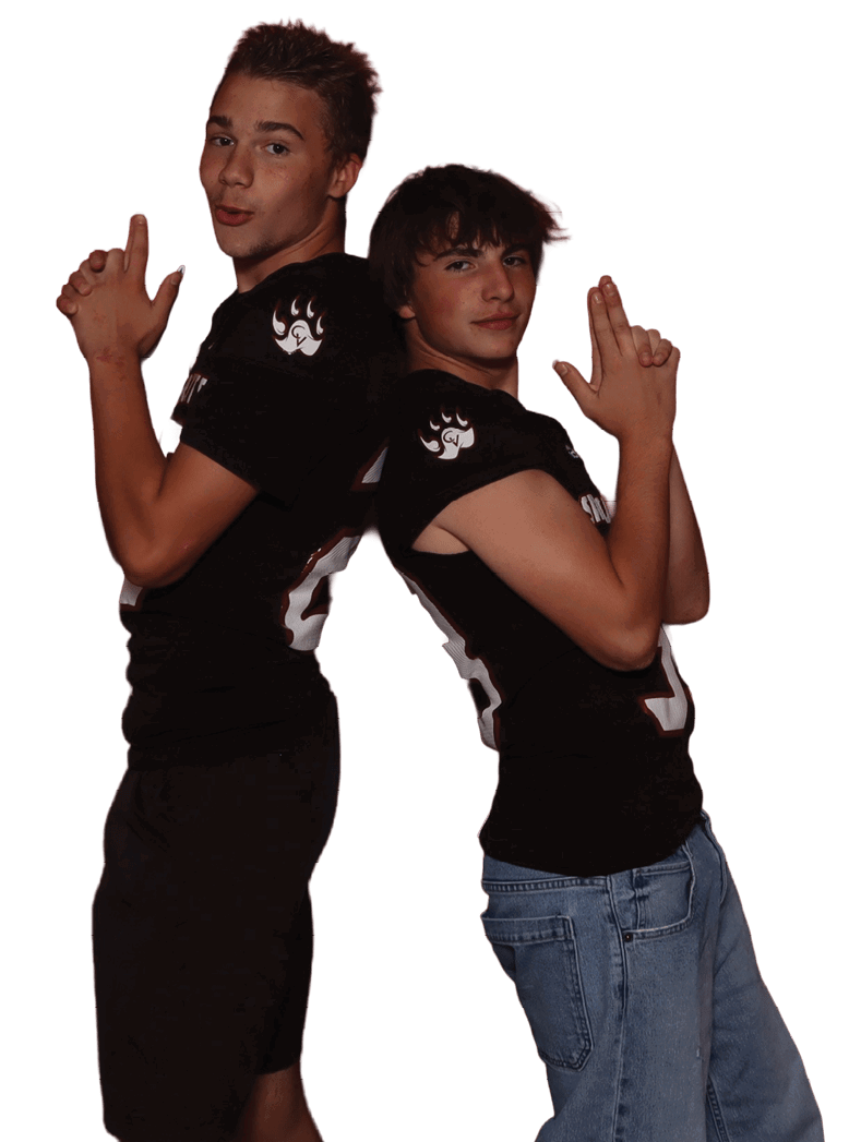 Two adults wearing black shirts pose back to back with their hands shaped like finger guns. Description generated by AI