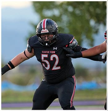 An athlete wearing a black football uniform with the number 52 and the words Castle View is in an action pose on a field. Description generated by AI