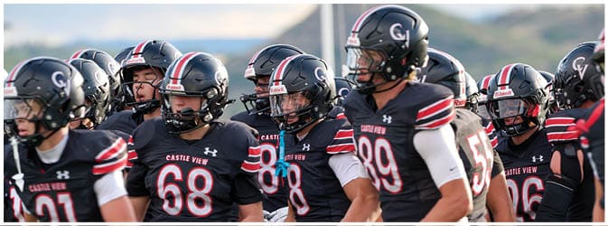 People wearing black sports uniforms with red and white stripes and numbers are standing closely together, some with gloves on. Description generated by AI
