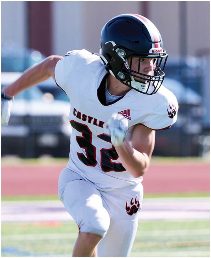 A person wearing a white football uniform with the number 32 and a black helmet is running on a football field. Description generated by AI