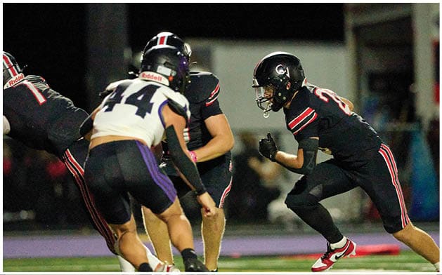 Several people wearing sports uniforms are actively running and competing on a football field. Description generated by AI