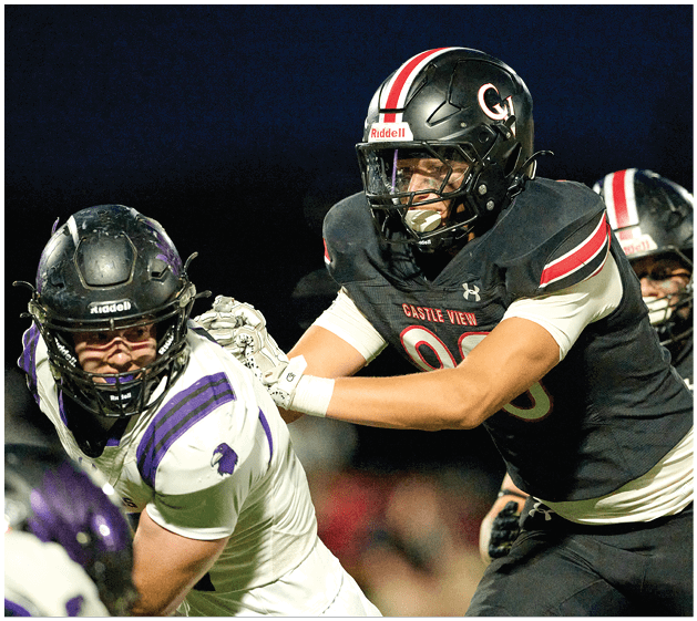 Two people in football uniforms are engaged in a play, with one person in a black uniform pushing against another person in a white uniform. Description generated by AI