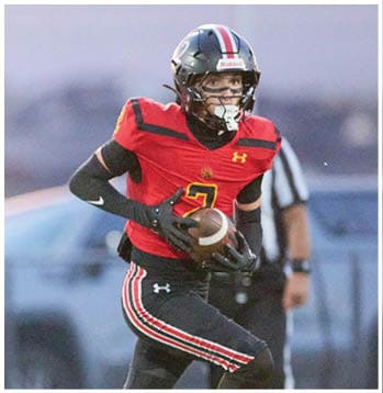 A person wearing a red and black football uniform with the number 2 is running while holding a football on a field. Description generated by AI