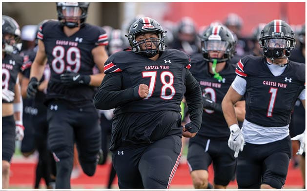 A group of people in black football uniforms with red and white accents are running on a field, with one person wearing number 78 leading the group. Description generated by AI