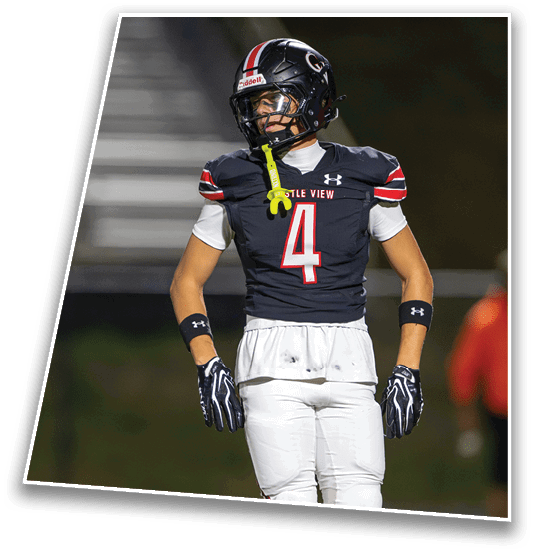 A person wearing a black and white football uniform with the number four stands on a field with hands on hips. Description generated by AI
