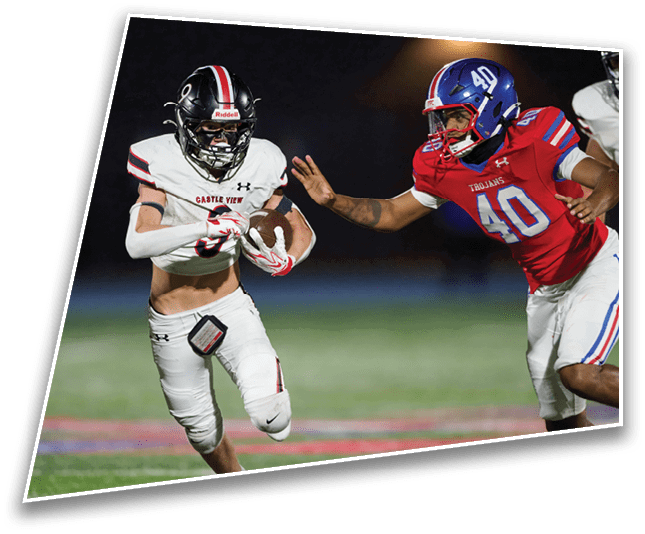 Two football players in action on a field at night with one player in white running with the ball and the other in red reaching out to tackle. Description generated by AI