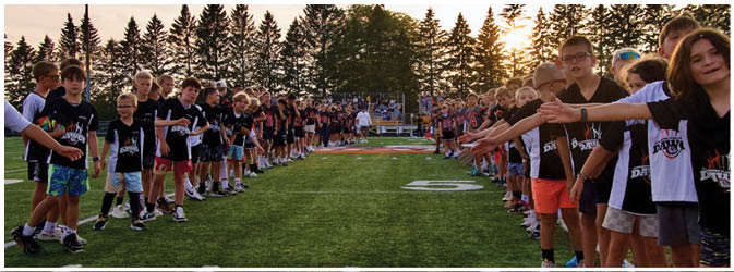 A football game is taking place on a field with players wearing blue and white uniforms. Description generated by AI
