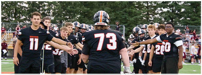 A football game is taking place on a field with players wearing blue and white uniforms. Description generated by AI