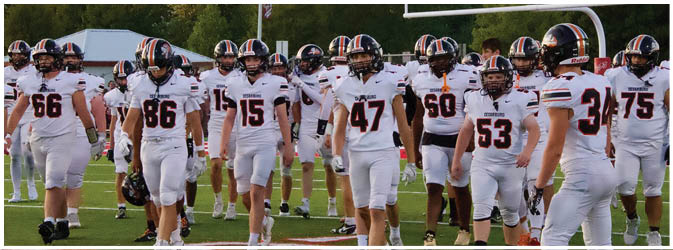 A football game is taking place on a field with players wearing blue and white uniforms. Description generated by AI