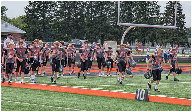 A football game is taking place on a field with players wearing blue and white uniforms. Description generated by AI