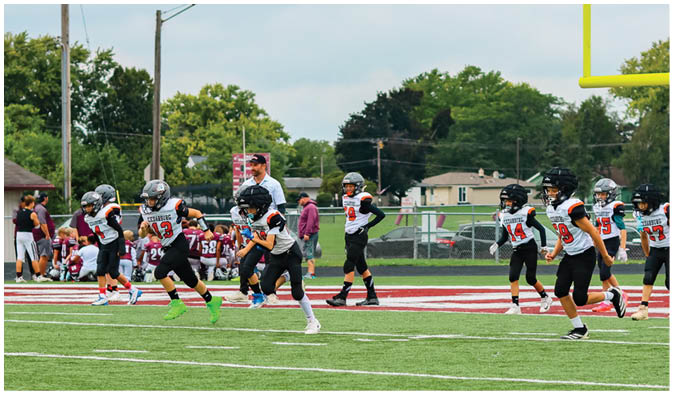 A football game is taking place on a field with players wearing blue and white uniforms. Description generated by AI